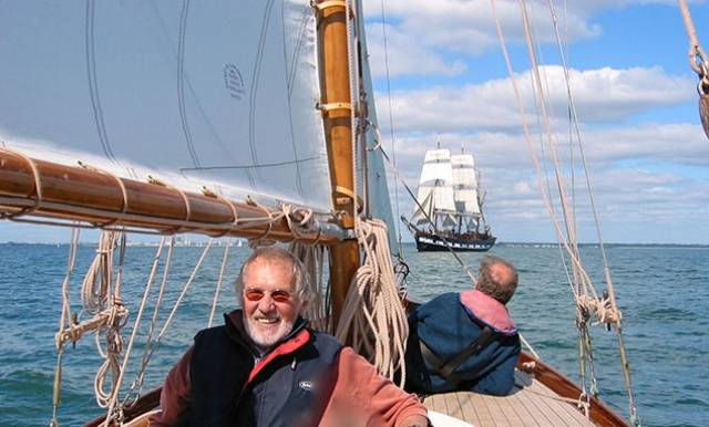 Hal Sisk aboard the newly-restored 1894-built Peggy Bawn in Dublin Bay in 2005, with the square-rigger Jeanie Johnston in the background. Peggy Bawn will be one of the stars of the Classics & Traditional section in the Volvo Dun Laoghaire Regatta 2017, celebrating the Bicentenary of the harbour. Photo: W M Nixon