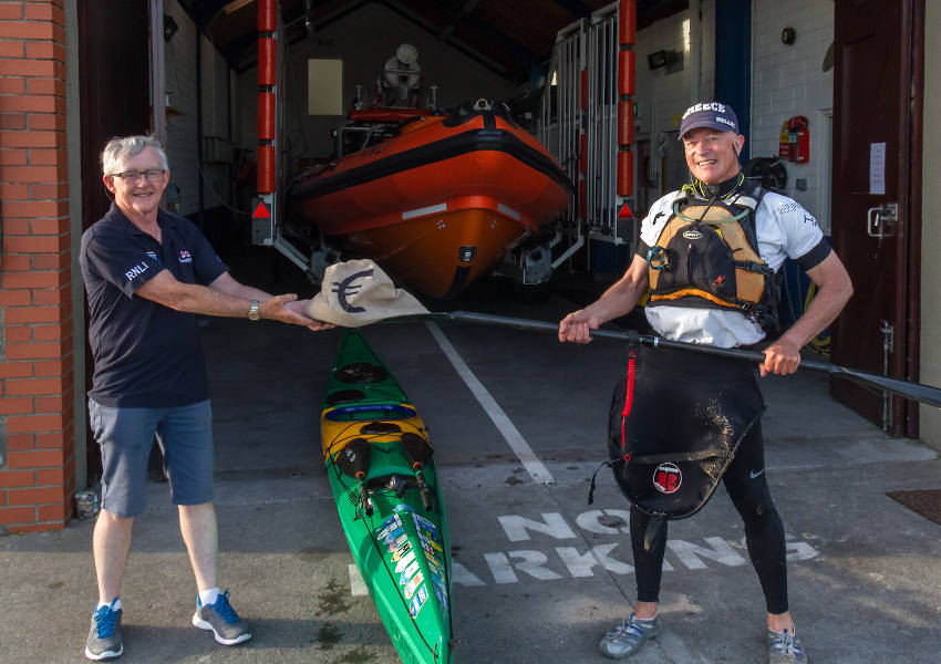 Kevin O’Sullivan using his paddle to pass the ‘Bag of Swag’ while maintaining social distancing (Photo: RNLI/Gerry Canning)