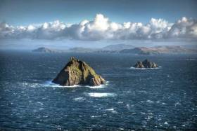 Skellig Michael, with the Little Skellig and the coast of Kerry beyond. The patch of white water in the foreground indicates the location of The Washerwoman Rock, and it has been demonstrated that it is possible to sail – indeed, to race – between it and the Skellig itself.
