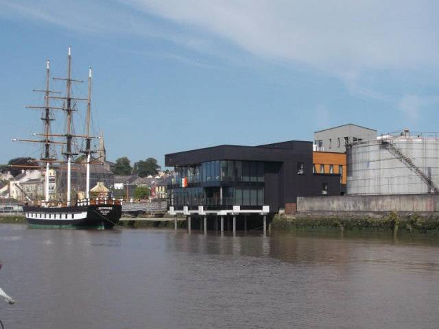 Famine replica museum ship Dunbrody alongside homeport of New Ross, Co. Wexford. New Ross Port is to be transferred to Wexford County Council within months. On the right oil tanks on the quay which are the subject of negotiations between the council and Department of Transport.