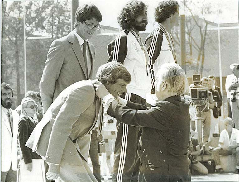 A moment of special peace in a troubled time. David Wilkins of Malahide receives his 1980 Olympic Silver Medal from IOC President Lord Killanin as his Flying Dutchman crew Jamie Wilkinson of Howth awaits his turn.
