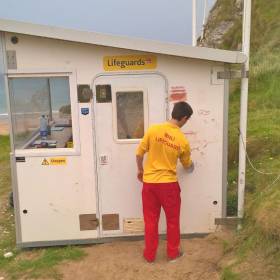A Whiterocks lifeguard cleans graffiti from the vandalised beach unit