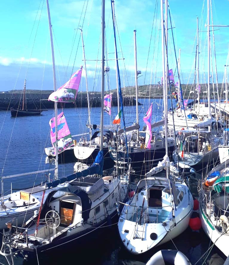 Escape to the islands…..late evening sunshine in Kilronan in the Aran Islands yesterday (Friday) evening as Galway Bay SC cruisers on their way to Roundstone and Inishbofin meet up with the Quinlan-Owens family in their Transatlantic-voyaging Danu. The lilac-pink banners indicate participation in the GBSC “Lambs Weekend”.
