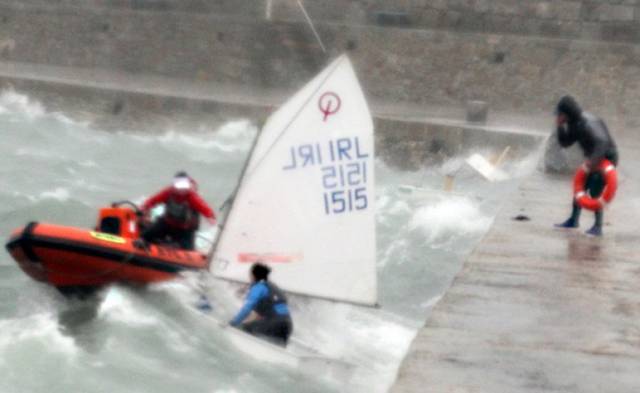 A RIB attempts a rescue of an Optimist Team Dinghy in Dun Laoghaire Harbour during Storm Brian last year. A person on the pier holds a lifebuoy. Two capsized Optimists are just visible in the top right of the picture. An independent report into the incident is published today