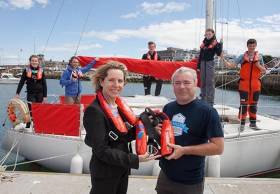 Bord Iascaigh Mhara (BIM) CEO Tara McCarthy presents one of the new compact lifejackets with  integrated personal locator beacon to Kyron O’Gorman, Principle of Irish Youth Sailing Club Dun  Laoghaire. Pictured in the background are Hannah Quigley (13) from Blackrock; Eugeen McCann  (Skipper), Kieran Hall (17) from Glenageary; Sorcha Duffy (13) from Deansgrange and Alan Roche  (15) from Dundrum