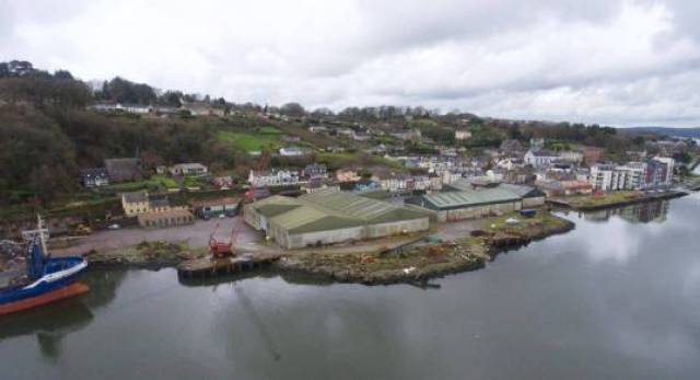 An 8-acre waterfront site up for sale at the former Royal Victoria Dockyard located in Passage West, Cork Harbour. The site is owned by Doyle Shipping Group (DSG). Afloat adds that the property includes a quay (see cargoship's bow) that extends eastward (not included in the photo) to the left.