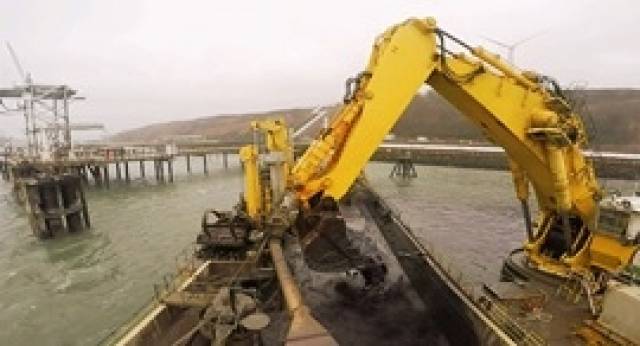 The giant bucket of the dredging vessel Mimar Sinan clears sediment from a jetty in the Port of Milford Haven