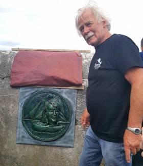 Dr Michael Brogan, Cruinniu organiser, with  the plaque of late Cruinniu founder Tony Moylan designed by John Coll and erected at Kinvara pier.