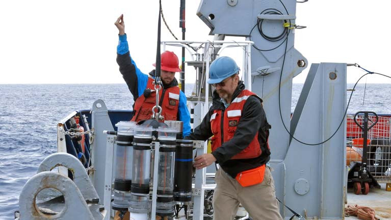 Marine chemist Ken Buesseler (right) deploys a sediment trap from the research vessel Roger Revelle during a 2018 expedition in the Gulf of Alaska. Buesseler's research focuses on how carbon moves through the ocean. Buesseler and co-authors of a new study found that the ocean's biological carbon pump may be twice as efficient as previously estimated, with implications for future climate assessments.