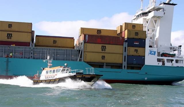 Camac, a Dublin Port pilot cutter launch with a containership underway in Dublin Bay 